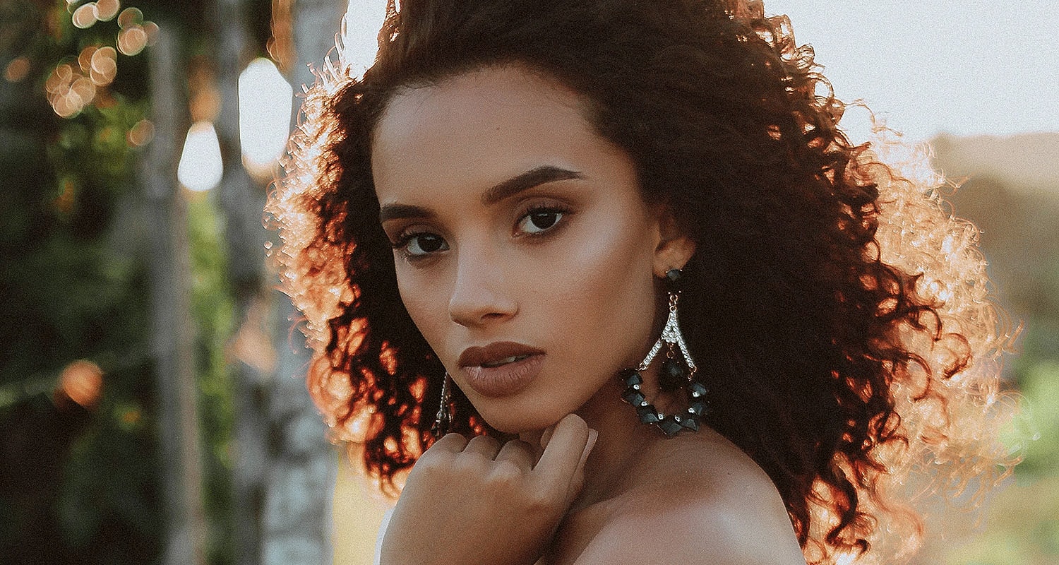 Woman with curly hair and elegant earrings. Pricing 