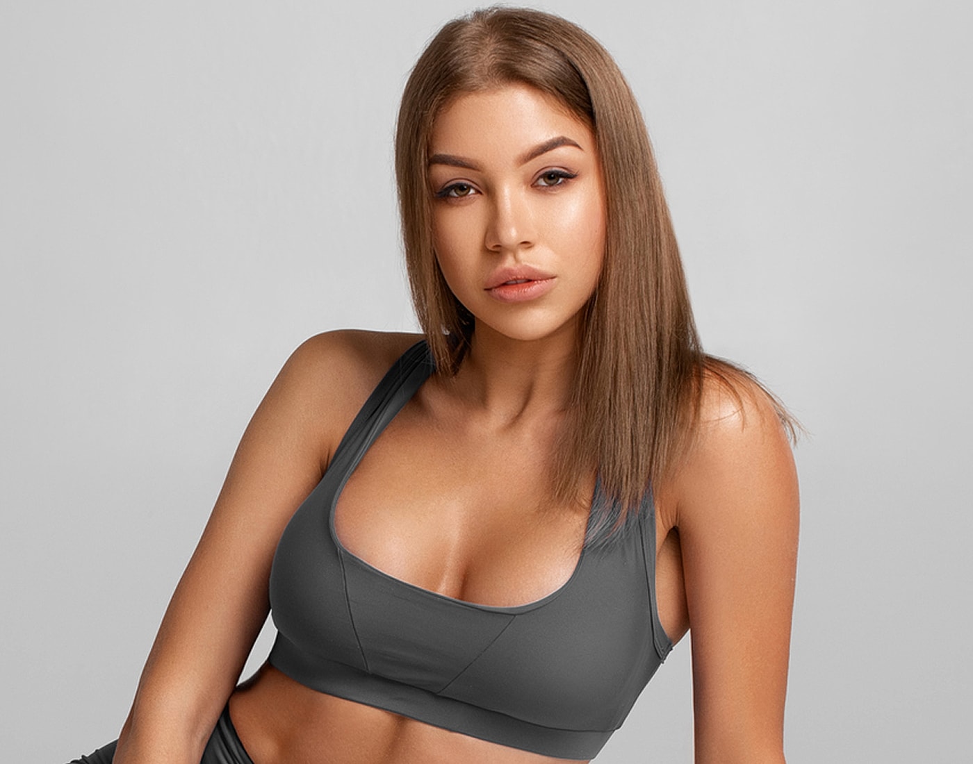 Model in gray sports bra, neutral background.