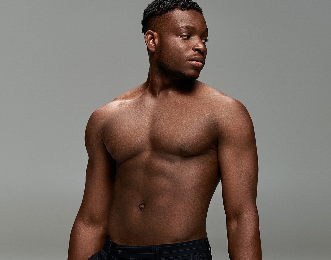 Man posing with shirtless, neutral background.