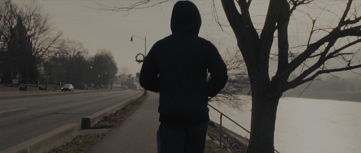 Person jogging along a quiet riverside path.
